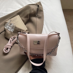 Detail view of light pink baguette bag with chunky silver chain on a soft white background