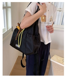 Detail of black nylon drawstring backpack with yellow dog charm and fashion label