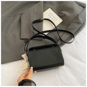 Détail du sac boîte en cuir grainé noir avec charm perle et clous dorés de protection