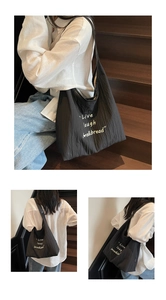 Dettaglio della borsa tote nera a pieghe con stampa bianca Live laugh love bread