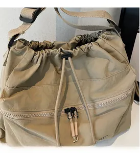 Detailed macro view of khaki drawstring crossbody bag with zip pocket and nylon fabric