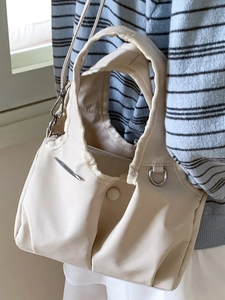Minimalist beige canvas shoulder bag with silver metal accents and crossbody strap