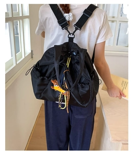 Detail of black nylon drawstring backpack with adjustable straps and cute dog charm