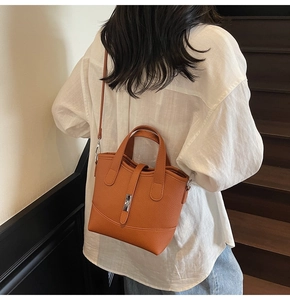 Caramel brown pebbled leather tote bag being carried by a model in a minimal indoor setting