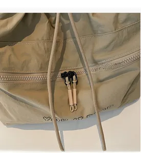 Detail of smooth double zipper closure with braided drawstrings on khaki nylon bag