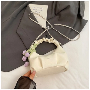 Détail d'un sac à main plissé crème avec pendentif tulipe et bandoulière en chaîne