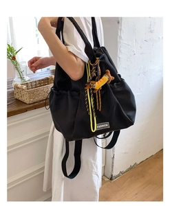 Detail of nylon drawstring backpack featuring yellow cords and a fashion woven label