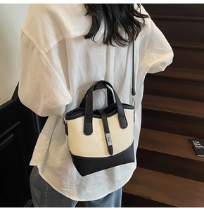 Close-up of a minimalist black and white leather bucket bag with metal turn-lock detail