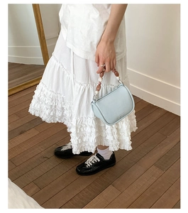 Detail view of light blue bucket bag featuring a colorful beaded handle and leather texture