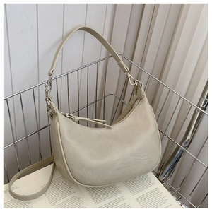 Detail of beige hobo bag with pleated texture and adjustable strap in a metal basket