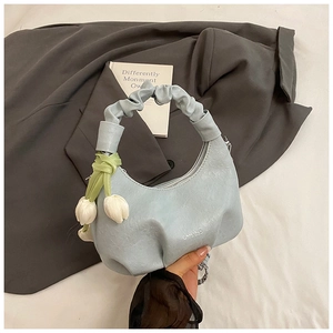 Détail du sac croissant bleu clair avec charme floral et poignée plissée élégante