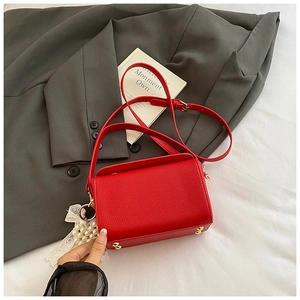 Détail du mini sac boîte en cuir grainé rouge avec clous dorés et breloque en perles