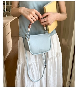 Detail of light blue lychee pattern leather bucket bag with marble bead handle decoration