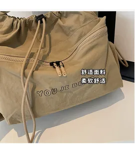 Detail of khaki nylon drawstring bag with soft pleats and zippered outer pocket