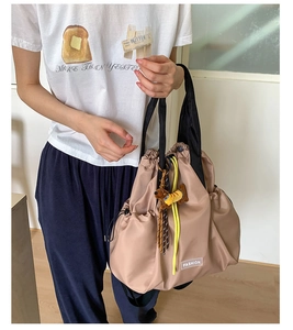 Detail of khaki nylon drawstring backpack with puppy pendant and fashion label on model