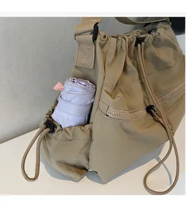 Detail of khaki nylon crossbody bag showing side pocket with a folding umbrella storage