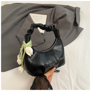 Détail d'un sac hobo noir avec poignée plissée et breloque tulipe dans un cadre chic