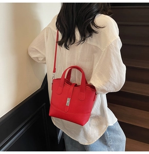Close-up of red leather tote bag with silver metal twist lock on a minimalist model