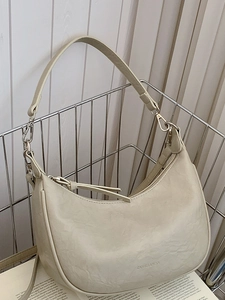 Minimalist creamy white crescent shoulder bag with pleated texture in a metal basket