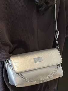 Silver metallic wrinkled leather baguette bag with chain strap shown on person