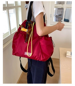 Detail of burgundy nylon backpack featuring yellow drawstrings and a cute dog charm accessory