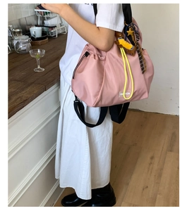 Pink drawstring nylon tote bag featuring yellow accents and cute decorative charms