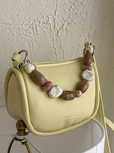 Pale yellow bucket bag with a chic multi-color beaded handle and textured leather finish