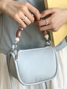 Light blue lychee leather bucket bag with unique beaded handle and adjustable shoulder strap