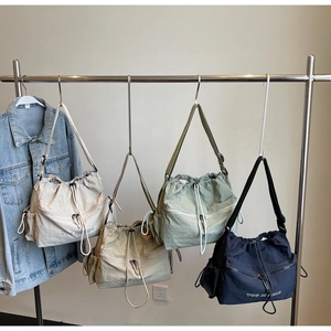 Detail view of nylon drawstring crossbody bags in beige, khaki, green, and navy colors