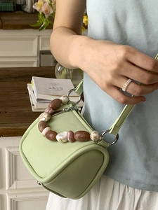 Light green cylindrical bucket bag with marble bead handle and thin leather shoulder strap