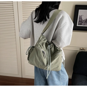 Detail of green nylon drawstring shoulder bag with You Just text and wide strap