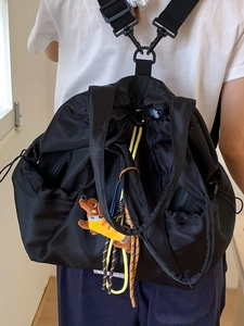 Black drawstring nylon backpack with yellow cord and cute dachshund plush toy charm