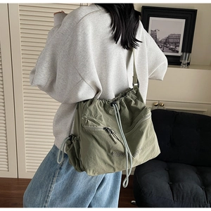 Close-up of green nylon crossbody bag with drawstring closure and You Bear embroidery