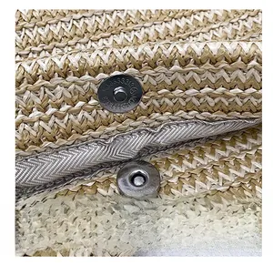 Detailed macro view of magnetic snap closure on beige woven straw tote bag surface