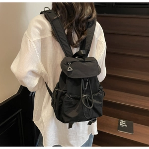 Outdoor style black backpack featuring drawstring closure and side pockets on model