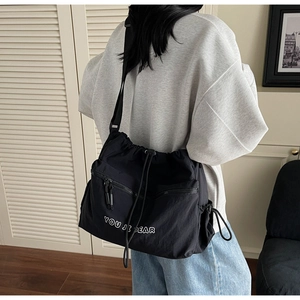 Detail shot of black nylon drawstring crossbody bag with adjustable strap and front zipper