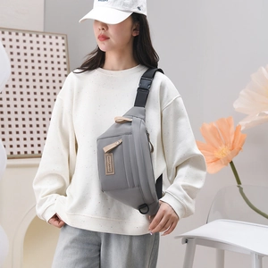 Détail d'un sac bandoulière en nylon gris avec logo et sangle noire réglable