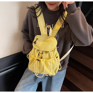 Detailed view of yellow nylon backpack featuring drawstring closure and flap with side pockets