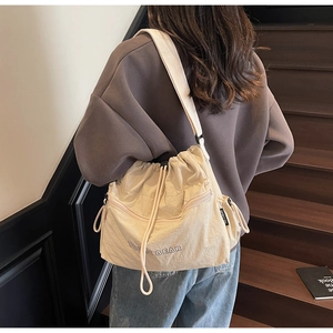 Detail of beige drawstring crossbody bag with YOU JI BEAR logo and wide shoulder strap