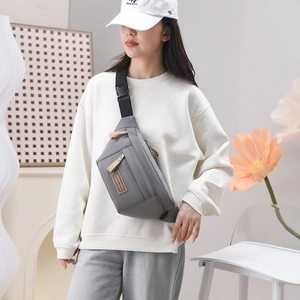 Détail du sac bandoulière en nylon gris avec sangle réglable et patch en cuir