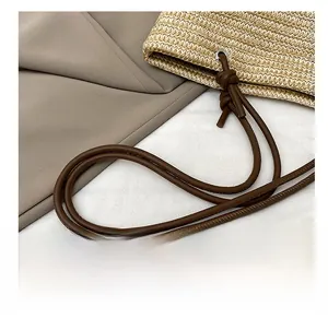 Close-up of woven straw tote with dark brown rope straps and metal eyelet details