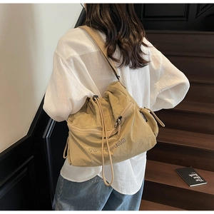 Detail view of large beige drawstring crossbody bag with side zipper and nylon texture