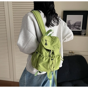 Lime green nylon backpack with flap drawstring closure and side pockets on a model