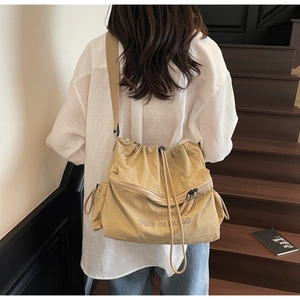 Rear view of model wearing a khaki drawstring nylon crossbody bag with wide strap
