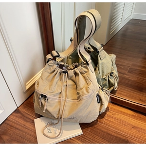Detail of beige nylon crossbody bag with drawstring closure and side logo tag