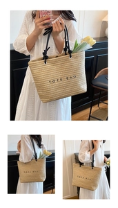 Detail of hand-woven straw tote bag with black letters and soft handles for summer