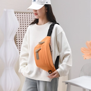 Gros plan d'un sac banane en nylon orange vif porté par un mannequin en intérieur chic