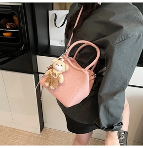 Détail du sac seau rose avec breloque ours et texture cuir dans un décor de style de vie