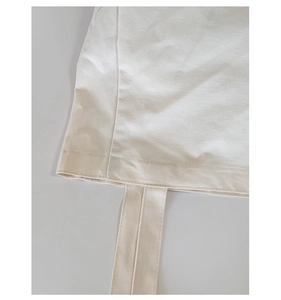 Detailed macro view of the reinforced stitching and heavy canvas texture on a cream tote bag