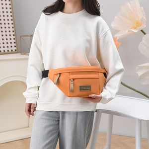 Détail d'un sac banane orange en nylon avec sangle ajustable et étiquette de marque